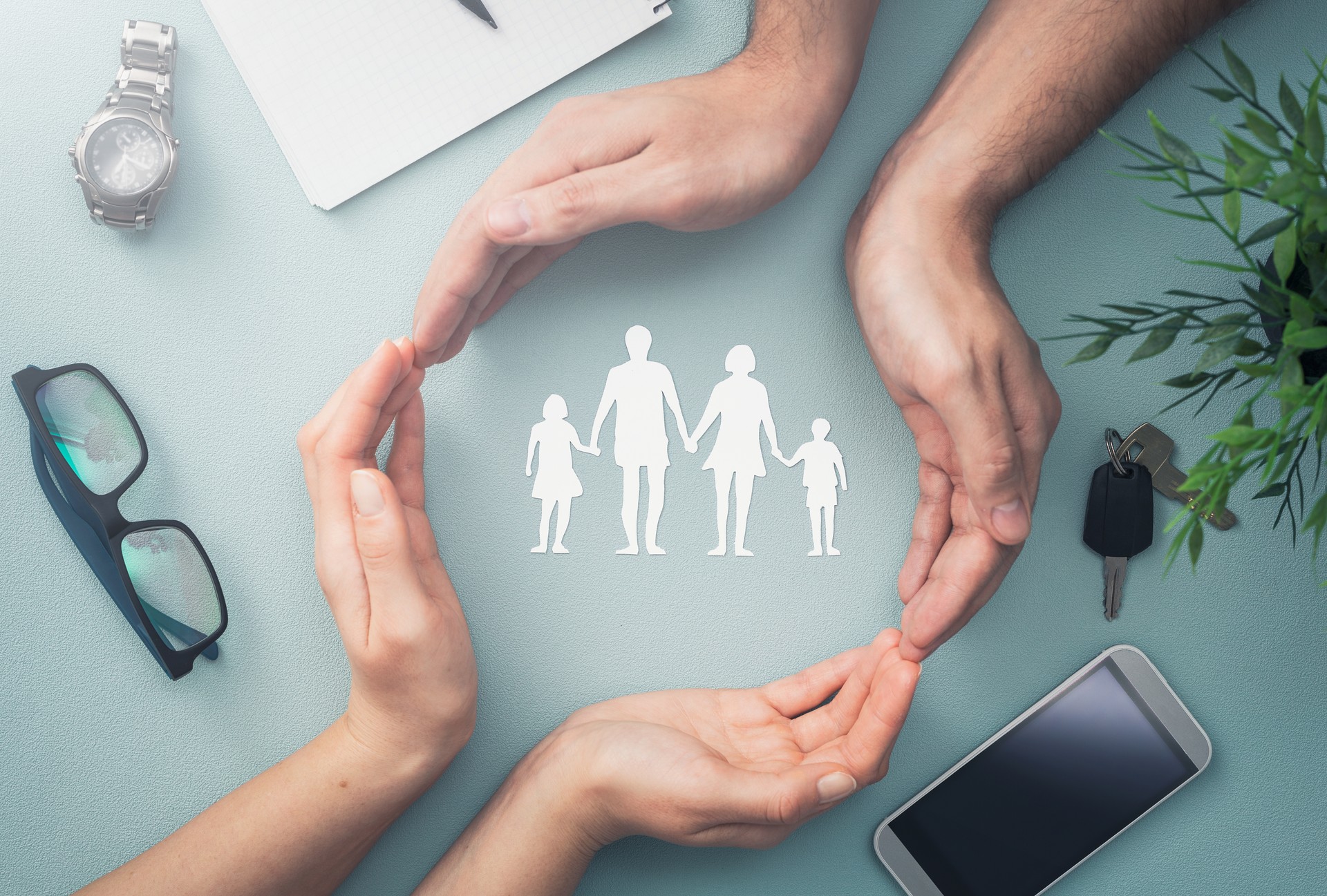 Family care concept. Hands with paper silhouette on table.