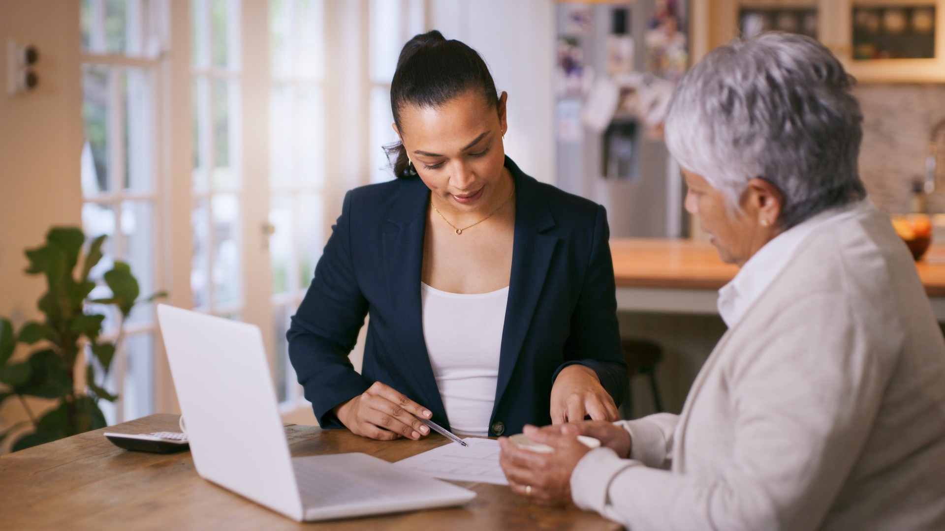 Shot of a consultant going through paperwork during a meeting with a senior woman at home